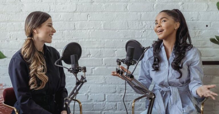 Host - Smiling African American female guest gesticulating while having interview with journalist sitting near mic