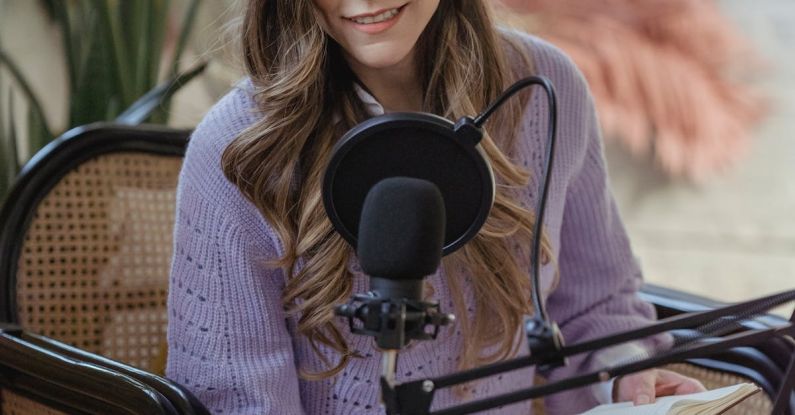 Hosting - Smiling woman recording podcast on microphone with laptop